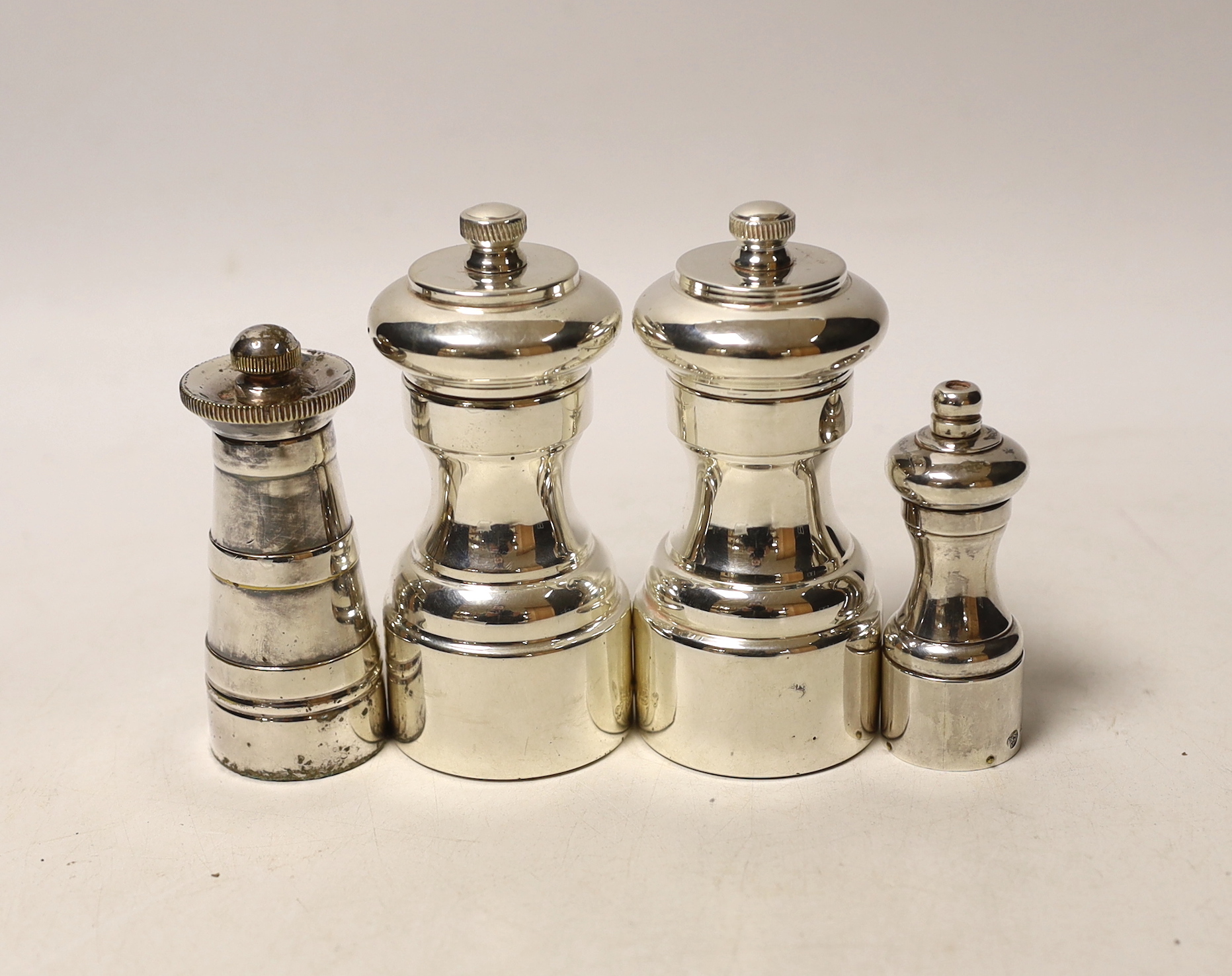 Three assorted modern silver pepper mills, largest 10.5cm and one plated pepper mill.